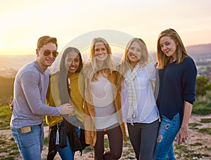 Friends are the family we choose. Portrait of a group of friends posing together while standing outside.