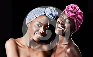 Friends in fashion. Studio portrait of two beautiful women wearing headscarves against a black background.