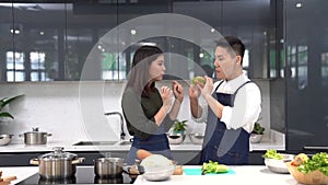 Friends are feeding each other. Young couples are helping to chop vegetables in the kitchen. Asian couple cooking together at the