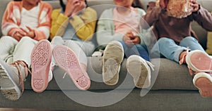 Friends, feet and children watching tv in the living room while sitting on a sofa in their home together. Family, legs