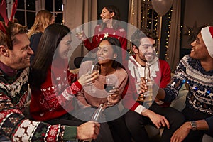 Friends In Festive Jumpers Celebrate At Christmas Party