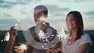 Friends with fireworks in their hands having fun at a party in the evening. Slow motion video