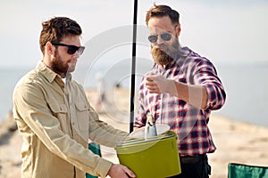 Friends with fish, bucket and fishing rod on pier