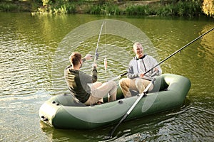 Friends fishing from boat on sunny day.