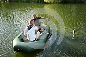 Friends fishing from boat on sunny day.