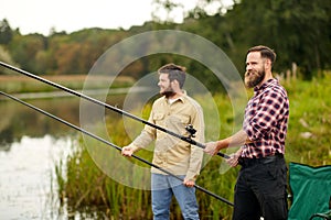 Friends with fishing rods at lake or river