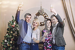 Friends of four men and women with bacale celebrate with champagne