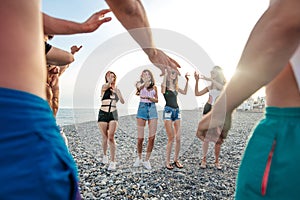 Friends dance on beach under sunset sunlight, having fun, happy, enjoy