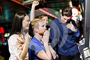 Friends gambling in a casino playing slot and various machines