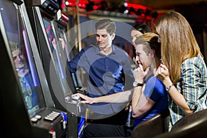 Friends gambling in a casino playing slot and various machines