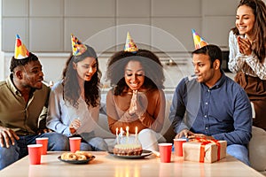 Friends gathered around birthday cake, have home party