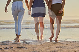 Friends, girl group and back at beach for walk on vacation, holiday or summer travel together in sunshine. Legs, holding