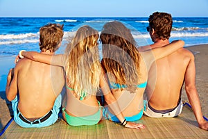 Friends group couples sitting in beach sand rear