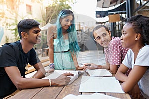 Friends, group and learning outdoor at university with books, listening and study for education on campus. Students, gen