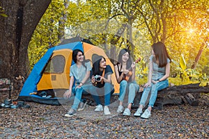 Friends Group of Young Asian women camping and resting at forest playing ukulele