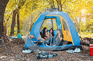 Friends Group of Young Asian women camping and resting at forest playing ukulele