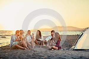 Friends with guitar at beach enjoyment. friends relaxing on sand