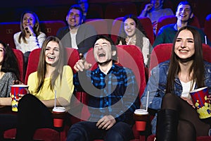 Friends of a guy and a girl are laughing loudly in a movie theater