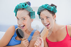 Friends in hair rollers singing into their hairbrushes