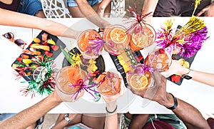 Friends hands toasting summer drinks at cocktail bar on happy hour