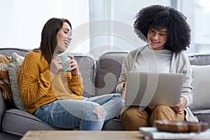 Friends, happy and sofa in house with laptop for social media, talking and online subscription. Women together, tech and