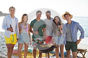 Friends having drinks by barbecue at beach