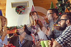 Friends having fun blowing party whistles while celebrating birthday