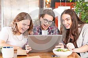 Friends having fun at cafe looking at tablet pc watching fun videos or having video call or social media. Three friends