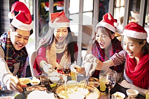 friends having fun and celebrating christmas in hot pot restaurant