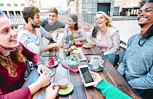 Friends having fun drinking cappuccino at coffeehouse - Young people talking together at restaurant cafeteria - New normal