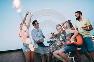 Friends having fun and drinking cocktails outdoor on a rooftop get together