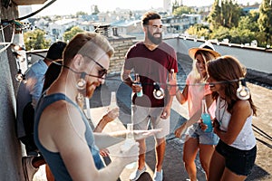 Friends having fun and drinking cocktails outdoor on a rooftop get together