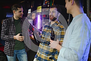 Friends having fun. Happy young men in casual wear drinking beer in pub.