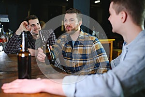 Friends having fun. Happy young men in casual wear drinking beer in pub.