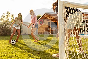 Friends having fun playing football barefoot on the lawn