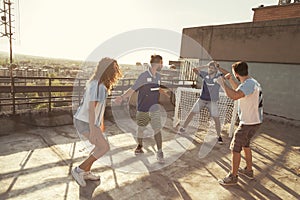 Friends having fun playing football on building rooftop terrace