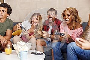 Friends having fun playing video games while spending leisure time together at home