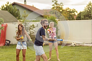 Friends having fun splashing water on each other with squirt guns