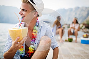 Friends having fun together at the beach and drinking cocktails