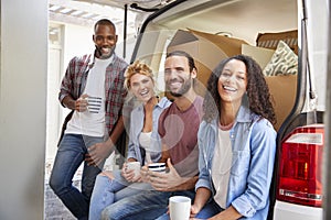 Friends Helping Couple To Unload Removal Truck On Moving Day