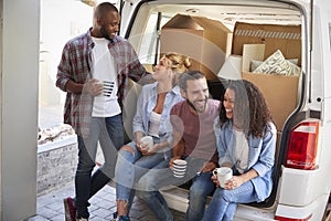 Friends Helping Couple To Unload Removal Truck On Moving Day