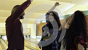 Friends high-fiving to each other at the bowling club