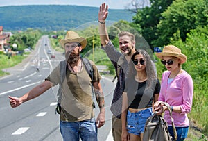 Friends hitchhikers travelling summer sunny day. Travellers try to stop car. Company friends travelers hitchhiking at