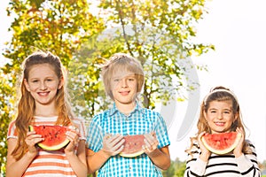 Friends hold watermelon and eating together in row