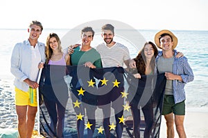 Friends holding European Union flag on shore at beach