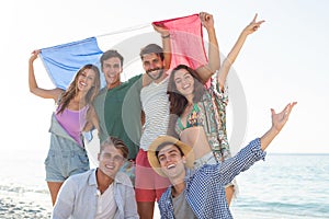 Friends holding French flag on shore at beach