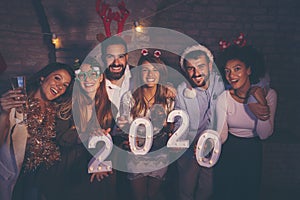 Friends holding illuminative numbers 2020 at New Years party