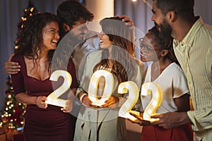 Friends holding illuminative numbers 2022 at New Years Eve midnight countdown