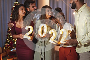 Friends holding illuminative numbers 2022 while celebrating New Year photo