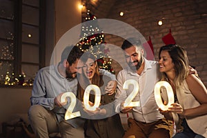 Friends holding illuminative numbers 2020 celebrating New Year photo